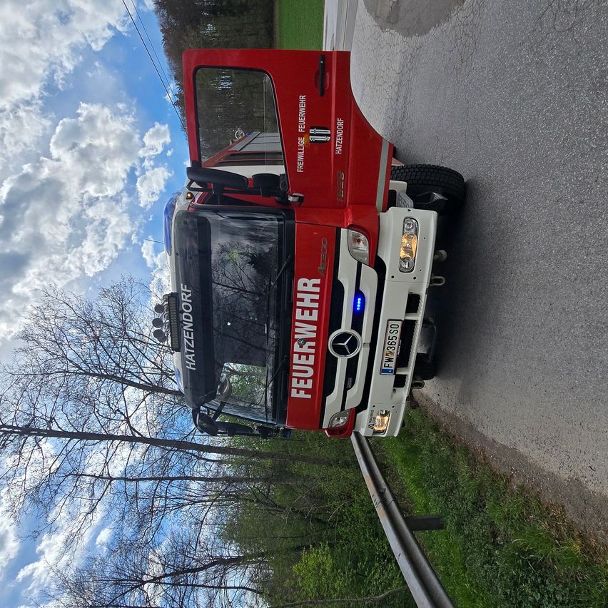 Ein roter Feuerwehrwagen mit dem Wort Feuerwehr an der Seite ist am Straßenrand geparkt.