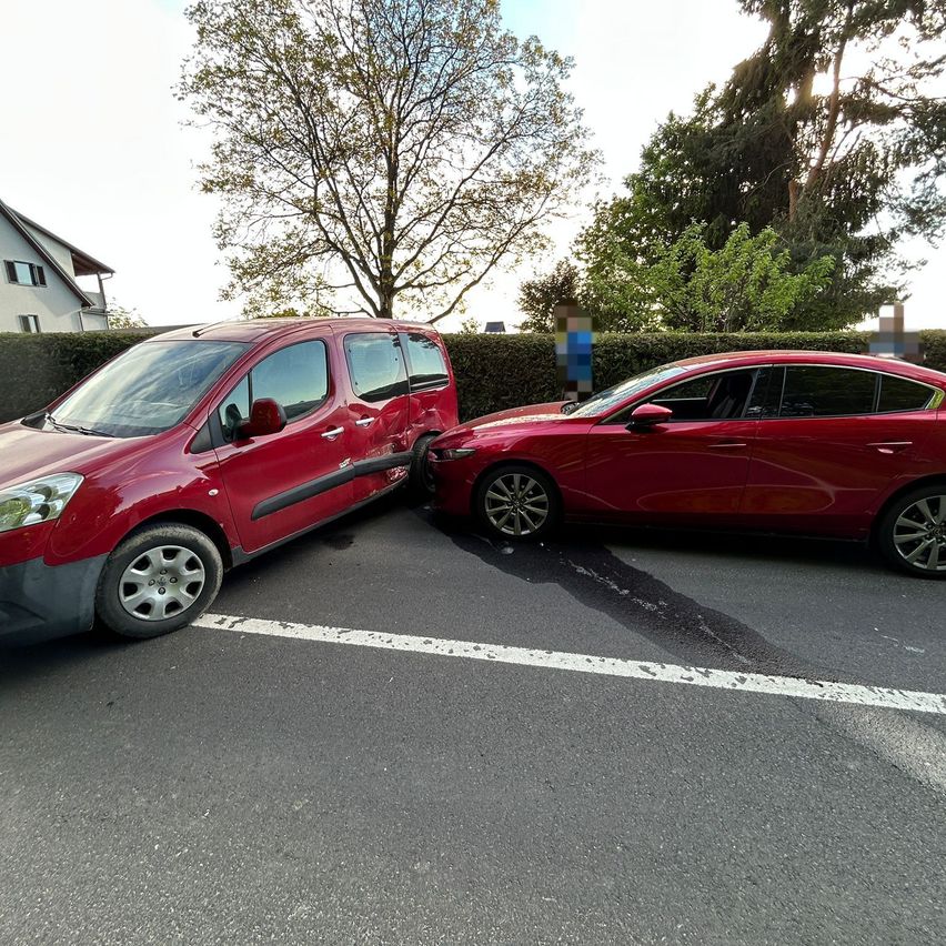 Zwei rote Autos sind auf der Straße geparkt. Ein Auto steht in einem Parkplatz, während das andere Auto die Seite davon getroffen hat.