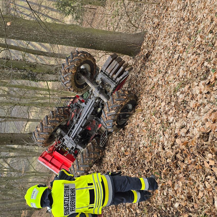 Ein Rettungssanitäter untersucht ein umgekipptes ATV im Wald. Das ATV liegt auf der Seite mit großen Reifen in der Luft.