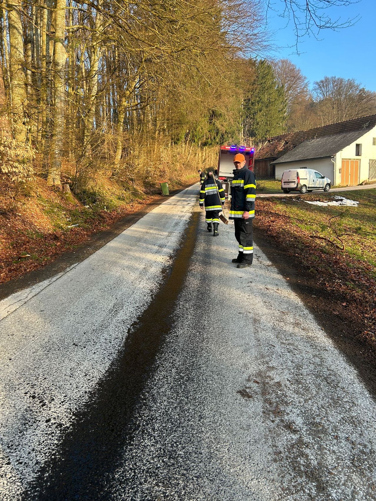 Feuerwehrleute gehen eine Straße entlang, wo ein Feuerwehrwagen geparkt ist, ein weißer Van ist vor einem Haus geparkt.
