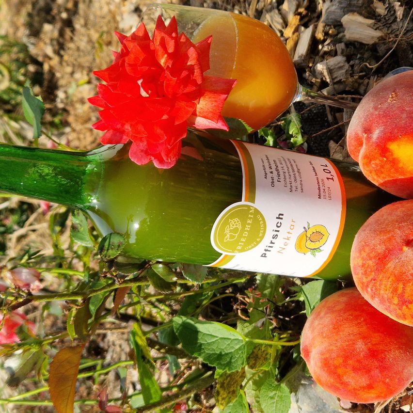 Eine grüne Flasche Nektar mit einer roten Blume und Pfirsichen auf dem Boden.