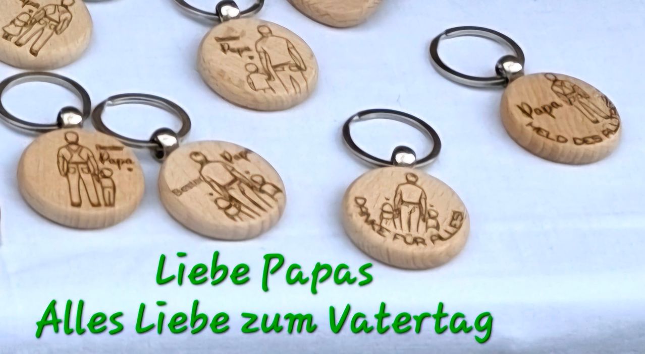 Eine Sammlung von Holz-Schlüsselanhängern mit einer Zeichnung einer Familie auf jedem. Der Text lautet 'Liebe Papas Liebe zum Vatertag.'