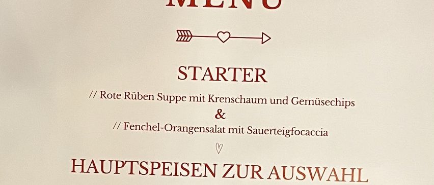 Valentinstagsmenü mit roter Suppe, Fenchel-Orangensalat und drei Hauptgerichten: Salt Beef Burger, panierter Lachs oder Rosa Ravioli. Dessert ist nicht erwähnt.