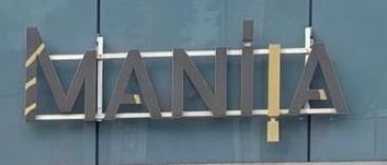 Die Eingangsfront eines Ladens namens Mania mit Glaswänden und Türen, außen ausgestellte Kleidungspuppen.