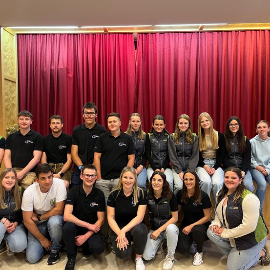 Eine Gruppe von Menschen in schwarzen und weißen Shirts posiert für ein Foto vor einem roten Vorhang.