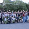 Eine Gruppe von Menschen in traditioneller Kleidung, einige mit grünen Röcken, posiert für ein Foto vor einem Gebäude.