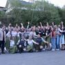 Eine Gruppe von Menschen in traditioneller Kleidung, einige mit grünen Röcken, posiert für ein Foto vor einem Gebäude.