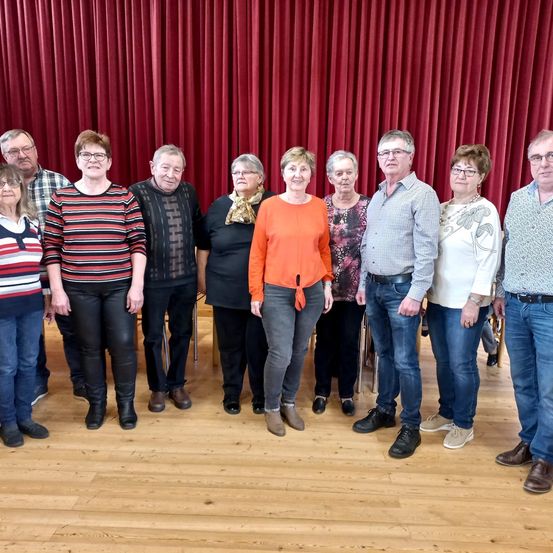 Eine Gruppe von Menschen in Freizeitkleidung, die vor einem roten Vorhang steht.