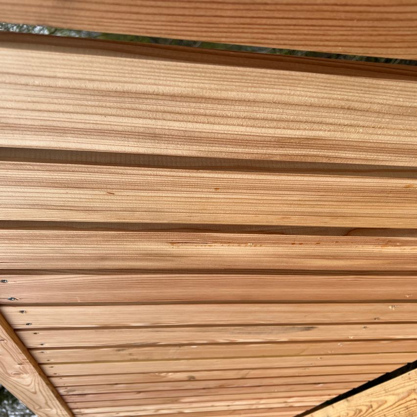 Eine Nahaufnahme von Holzbrettern mit sichtbarer Maserung und Nagelköpfen, die eine strukturierte Oberfläche zeigen.