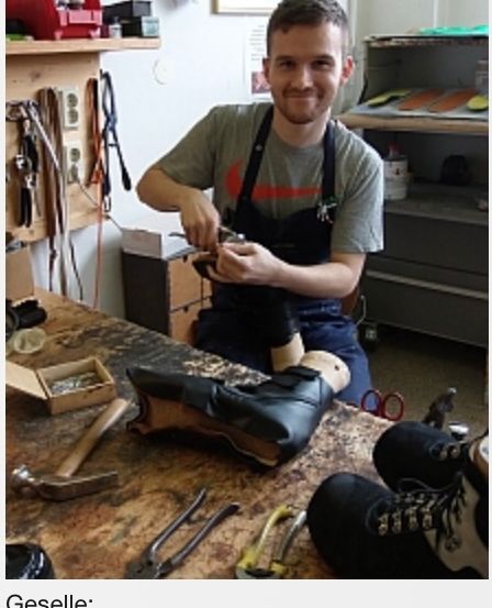 Ein Mann, David Oberwimmer, sitzt mit Werkzeug und Schuhen an einem Werktisch und lächelt in die Kamera.