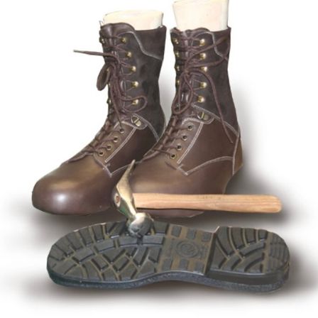Zwei braune Lederstiefel mit Messingschnürsenkeln und einem Hammer auf einer Stiefelsohle mit einem Profilmuster.