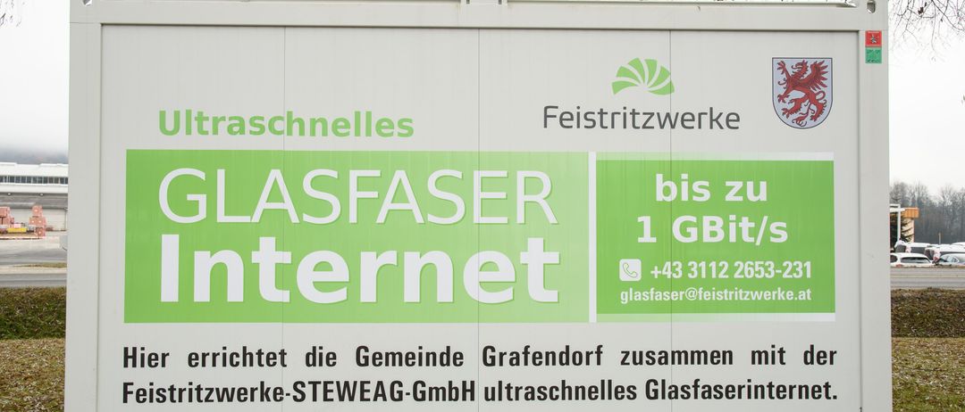 Ein Werbeschild für ultraschnelles Internet von Glasfaser Internet, das Geschwindigkeiten bis zu 1 GBit/s bietet, mit Kontaktinformationen und einer Gemeinschaftspartnerschaft mit Grafendorf und STEWEAG GmbH.