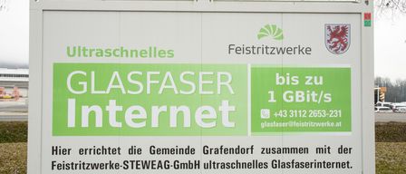 Ein Werbeschild für ultraschnelles Internet von Glasfaser Internet, das Geschwindigkeiten bis zu 1 GBit/s bietet, mit Kontaktinformationen und einer Gemeinschaftspartnerschaft mit Grafendorf und STEWEAG GmbH.