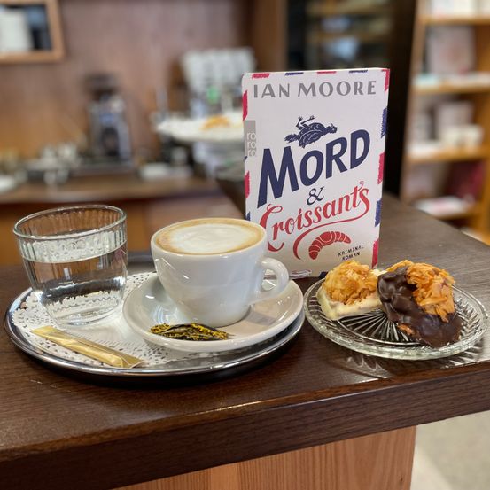 Bild enthält, Saucer, Cafe, Indoors, Restaurant, Cup, Coffee Cup, Book, Publication, Table, Tabletop