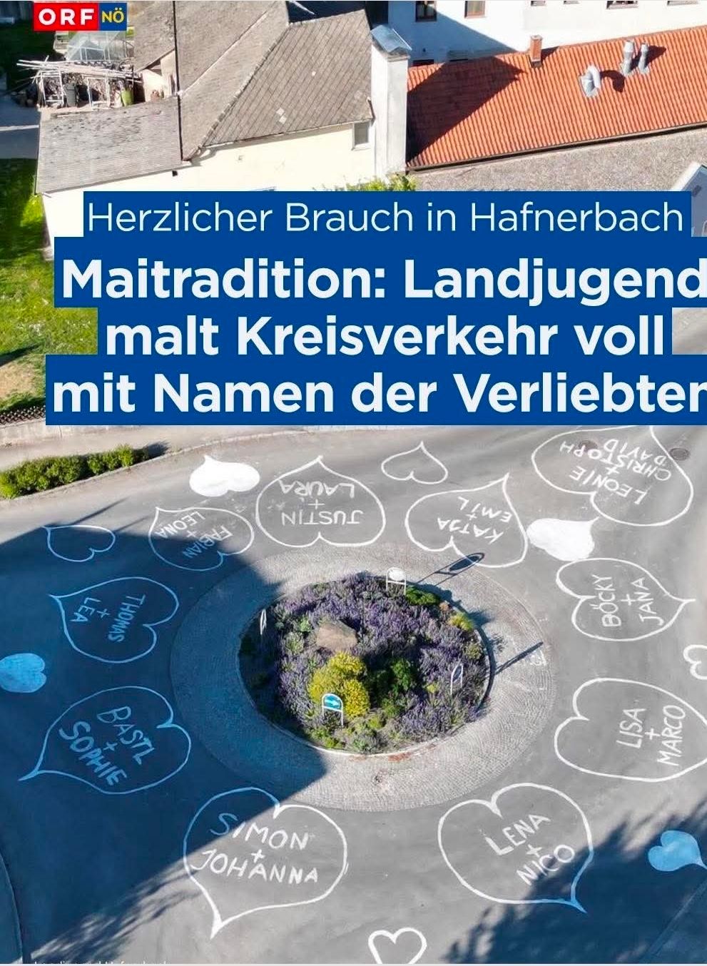 Luftaufnahme eines Kreisverkehrs in Hafnerbach mit Herzen und Namen auf der Straße gemalt. Ein blauer Banner steht oben 'Herzlicher Brauch in Hafnerbach'.