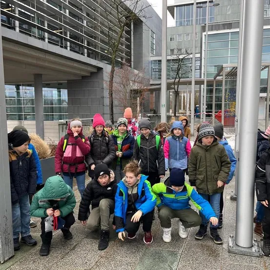 Eine Gruppe von Kindern in Winterkleidung posiert für ein Foto vor einem modernen Gebäude.