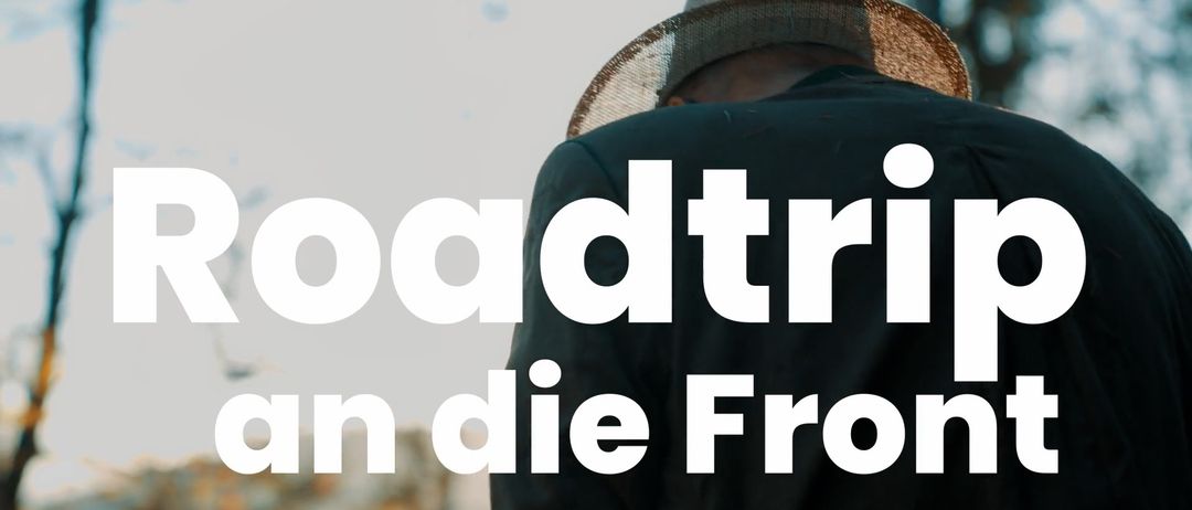 Ein Mann in einem Hut mit den Worten 'Roadtrip' in weißem Text auf schwarzem Hintergrund.