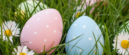 Mehrere Ostereier mit gepunkteten Mustern liegen im Gras, in der Nähe von Gänseblümchen. Ein blaues Rechteck in der oberen linken Ecke steht für 'in Breitenstein'.