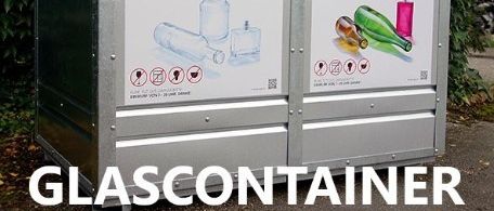 Ein Metallrecyclingbehälter mit zwei Kammern. Die linke ist für weißes Glas, die rechte für farbiges Glas. Er befindet sich auf einer Straße mit grüner Vegetation.