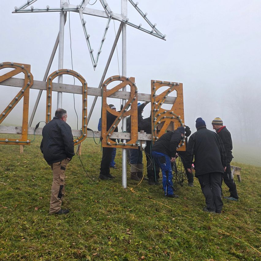 Eine Gruppe von Menschen arbeitet an einem großen Schild für das Jahr 2020 auf einem nebligen Feld.