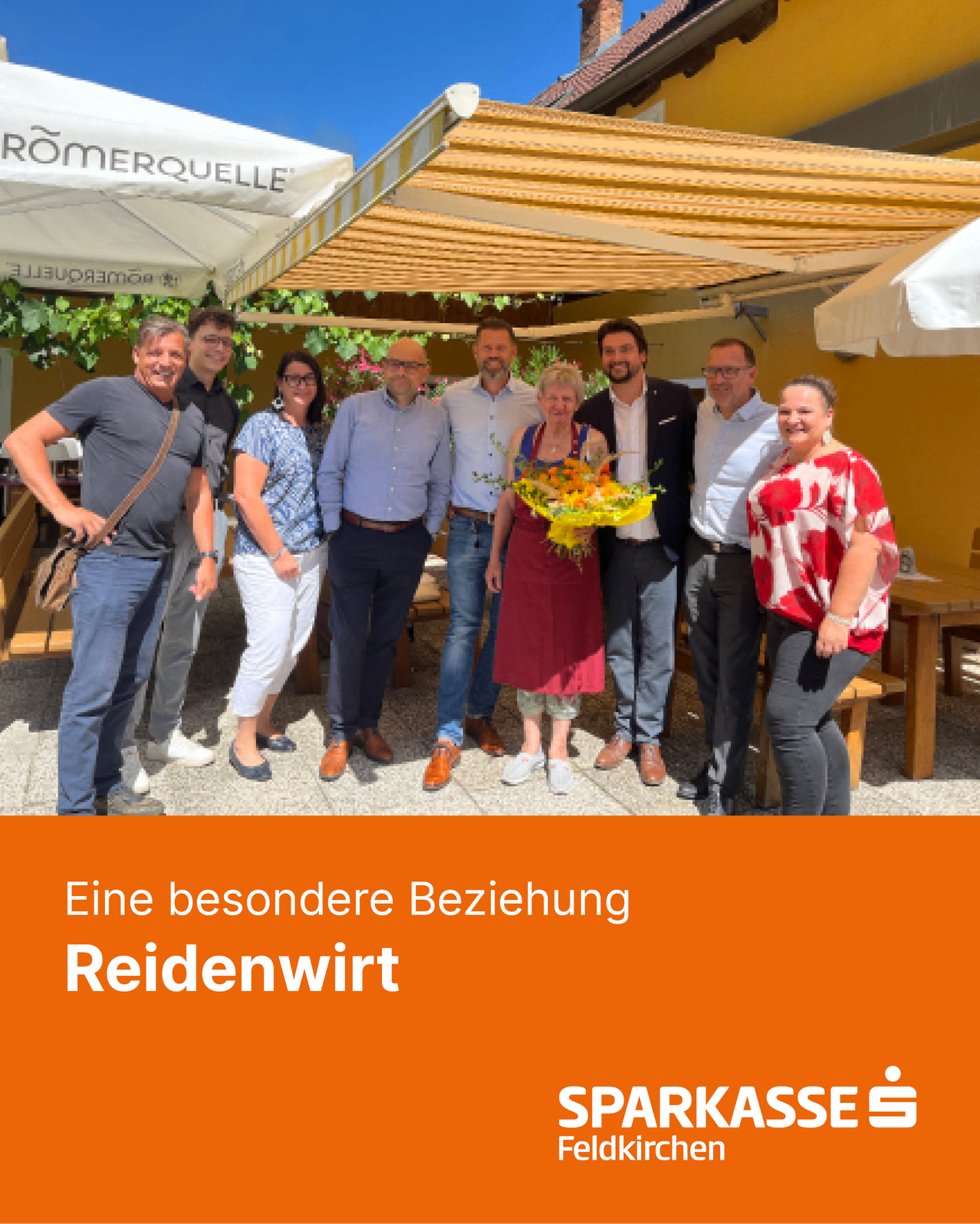 A group of people standing under a white canopy, smiling for a photo. A woman in a red dress holds a bouquet of flowers. The text 'Eine besondere Beziehung' and 'Reidenwirt' is displayed.