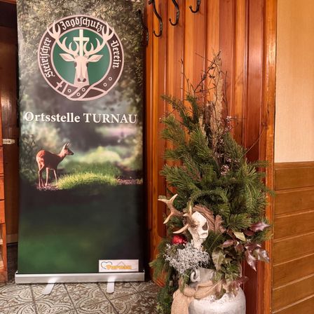 Ein Plakat für Ortstelle Turnau mit einem Hirsch und einem Kranz an der Wand.