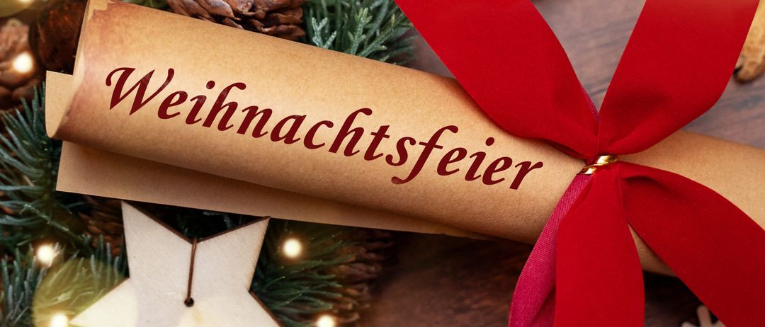 Ein gerolltes Stück braunes Papier mit dem Wort 'Weihnachtsfeier' in Rot geschrieben, mit einem roten Band gebunden, umgeben von Weihnachtsdekorationen.