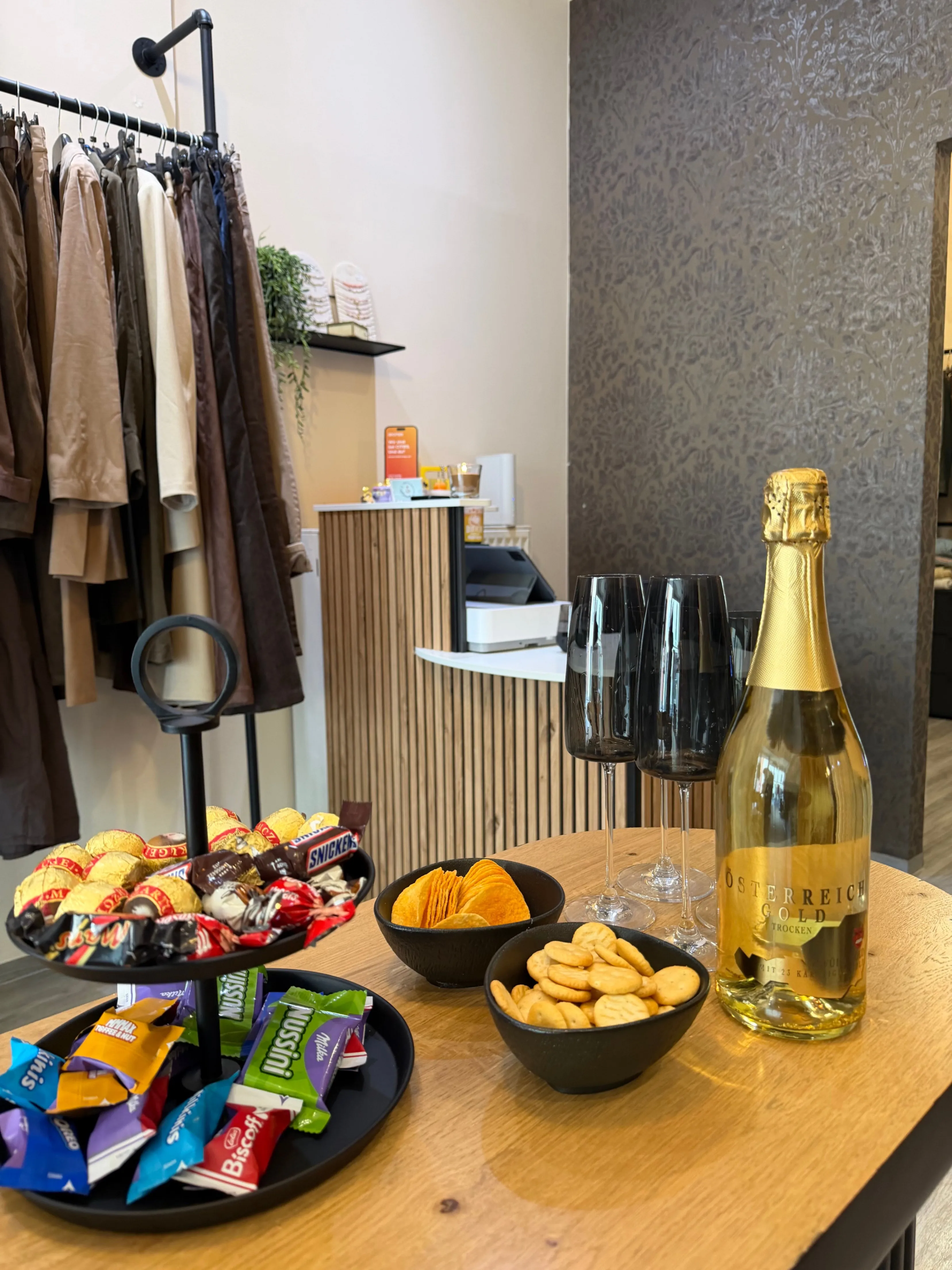 Ein Holztisch mit einer Flasche Champagner, einer Schüssel mit Crackern und einer Schüssel mit Keksen.