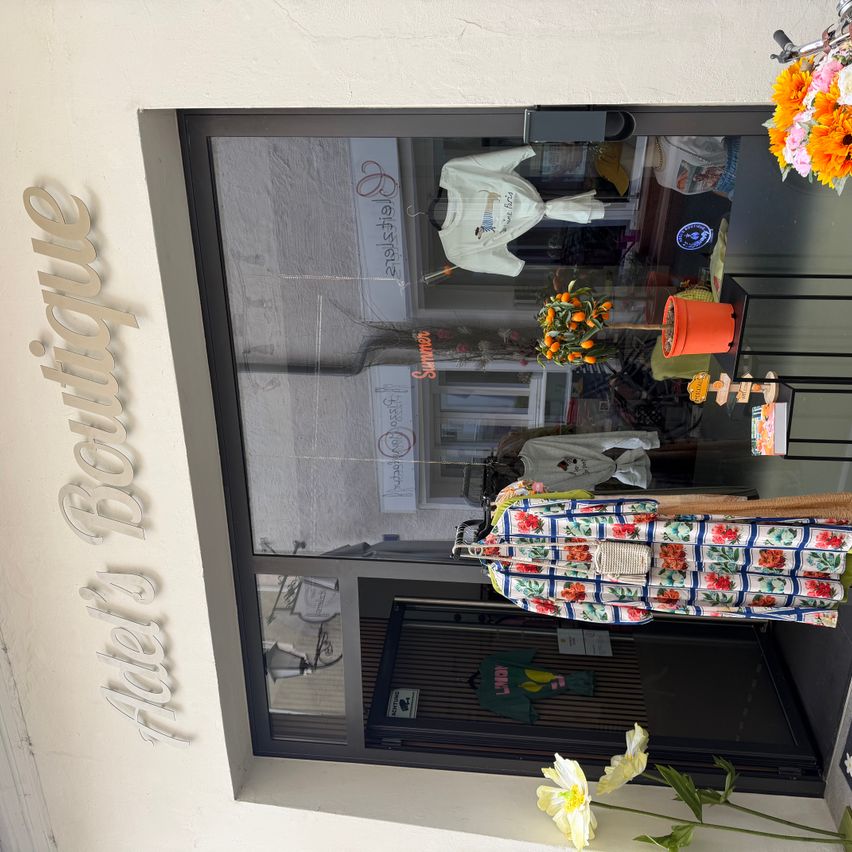 Ein Boutique-Laden zeigt Blumenkleider und andere Artikel im Schaufenster. Der Name des Ladens, Abel's Boutique, steht an der Wand.
