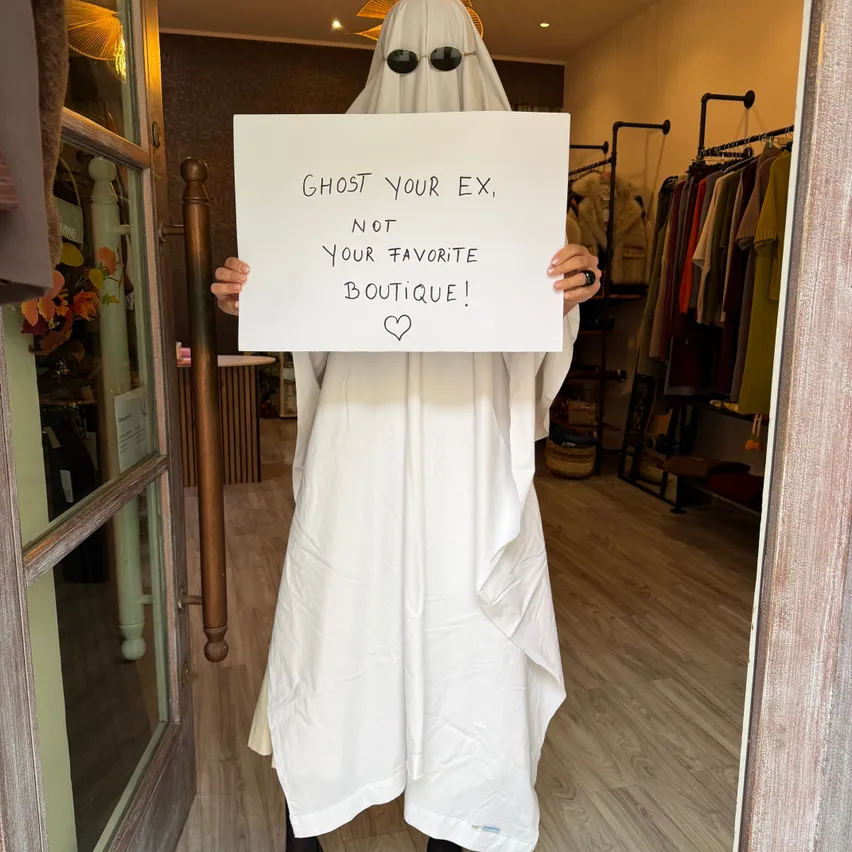 Eine Person, die als Geist verkleidet ist und ein Schild hält, auf dem steht 'Vergessen Sie Ihren Ex, nicht Ihr Lieblingsgeschäft!'