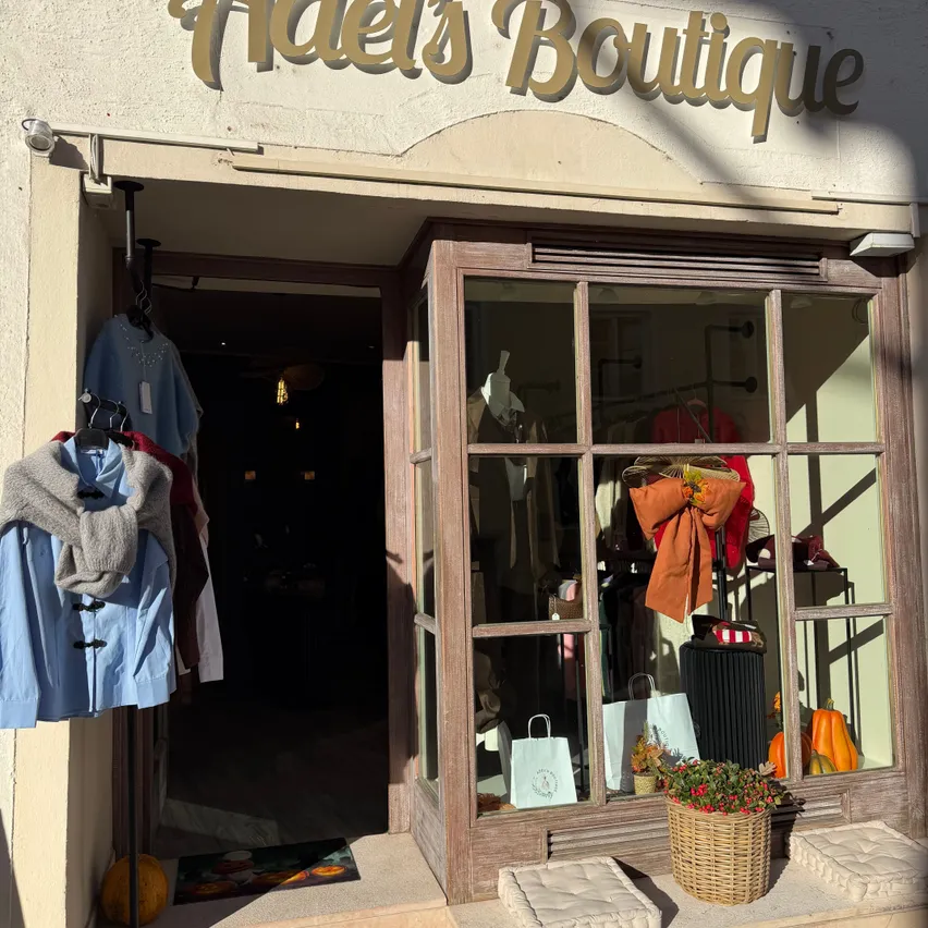 Die Vorderseite von Adel's Boutique, einem Bekleidungsgeschäft mit einer Glastür und Fenster, das verschiedene Kleidungsstücke und Accessoires präsentiert.
