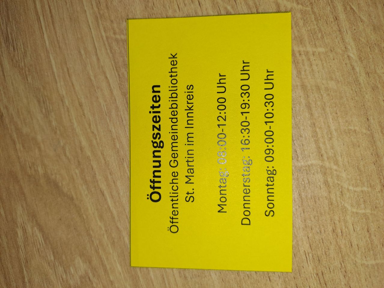 Eine gelbe Karte zeigt die Öffnungszeiten einer Bibliothek in Inkreis, einschließlich Tage und Zeiten.