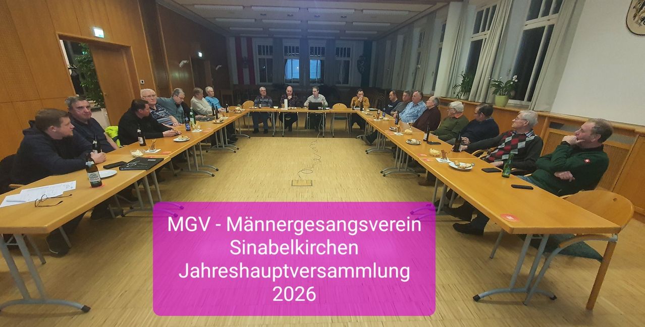 Eine Gruppe von Männern sitzt an Tischen in einem Besprechungsraum. Ein lilafarbener Banner am unteren Rand zeigt 'MGV - Männergesangverein Sinabelkirchen Jahreshauptversammlung 2026'.