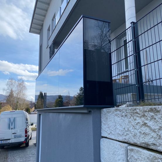 Ein modernes Haus mit einer Glaswand und Metallgittern. Ein Van ist auf der Straße davor geparkt.