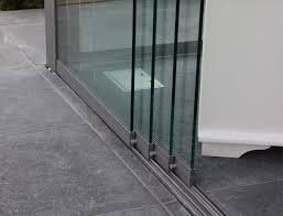 Eine Nahaufnahme einer Glasschiebetür mit silbernen Griffen, auf einem gefliesten Boden, die ein weißes Objekt auf dem Boden reflektiert.