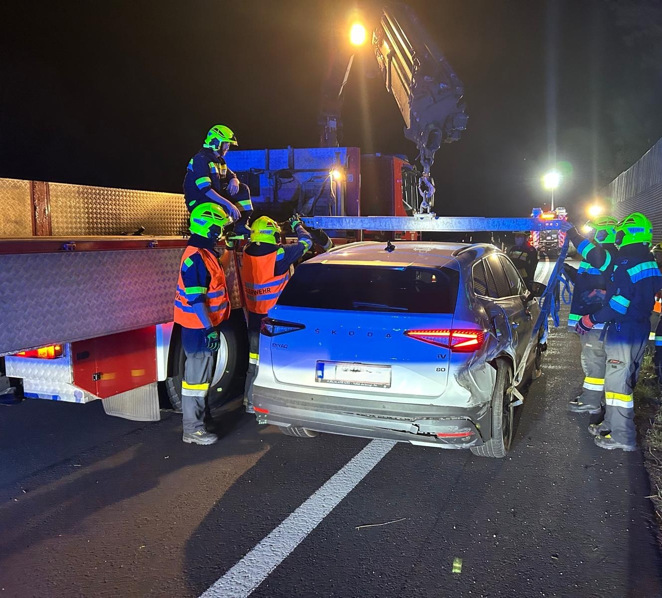 Feuerwehr sichert beschädigten Skoda nach Unfall auf der Autobahn bei Nacht