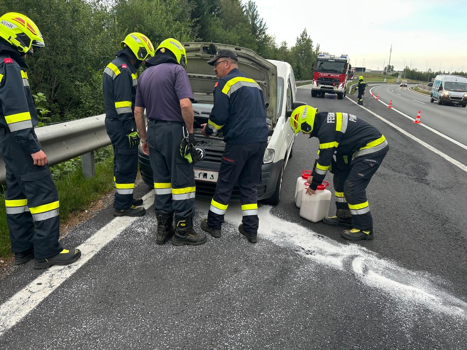 Feuerwehrleute sichern Einsatzstelle auf Autobahn mit weißem Pulver und Kanistern