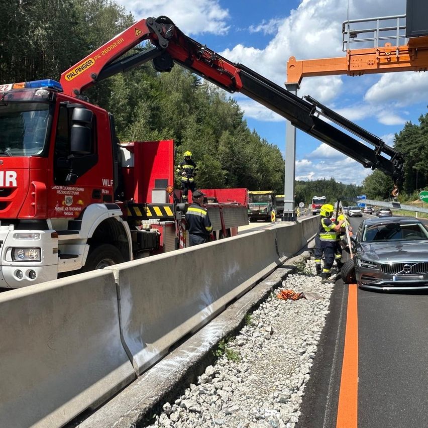 Feuerwehrleute benutzen einen Kran, um ein beschädigtes Auto von der Seite einer Autobahn zu entfernen.