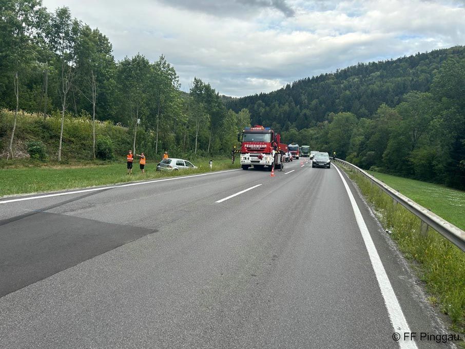 A road with a fire truck and emergency vehicles on the side, with two people in orange vests standing by a car.