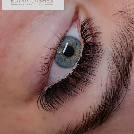 Ein Nahaufnahme eines Augens mit langen, gewellten Wimpern, die die Details der Wimpernverlängerungen hervorheben.