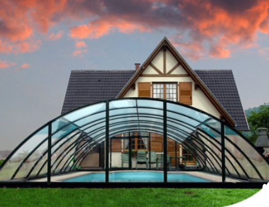 Ein modernes Haus mit einer Glaspoolabdeckung steht vor einem bunten Himmel. Das Haus verfügt über ein Giebeldach und braune Fensterläden.
