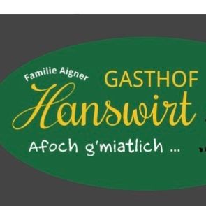 Ein grünes ovales Logo für ein familiengeführtes Gasthaus, Gasthof Hanswirt, mit einer stilisierten Illustration von zwei Männern mit einer Ziege. Darunter steht der Text 'Afoach g'miatlich...'.