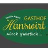 Ein grünes ovales Logo für ein familiengeführtes Gasthaus, Gasthof Hanswirt, mit einer stilisierten Illustration von zwei Männern mit einer Ziege. Darunter steht der Text 'Afoach g'miatlich...'.