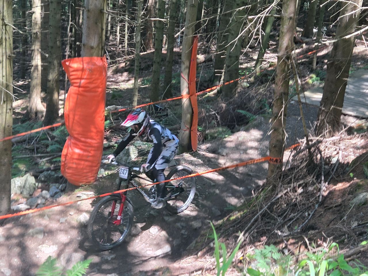 Ein Mountainbiker fährt durch einen Wald mit der Nummer 147 auf seinem Fahrrad und navigiert um orangefarbene Barrieren herum.