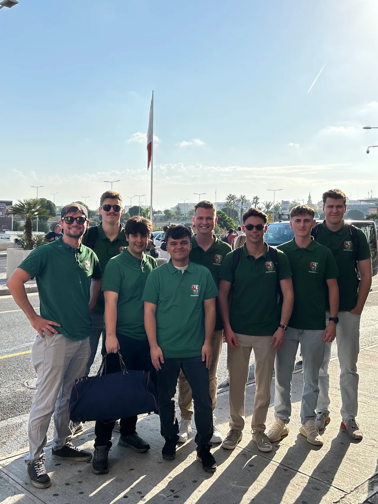 Eine Gruppe von Männern in grünen Polo-Shirts steht zusammen auf einem Bürgersteig.