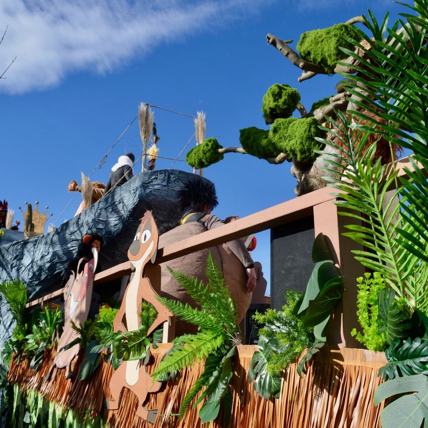 Ein Floß mit Dschungel-Thema, das Cartoon-Charaktere wie Timon und Pumbaa zeigt, mit einer Person im Hintergrund unter einem blauen Himmel.