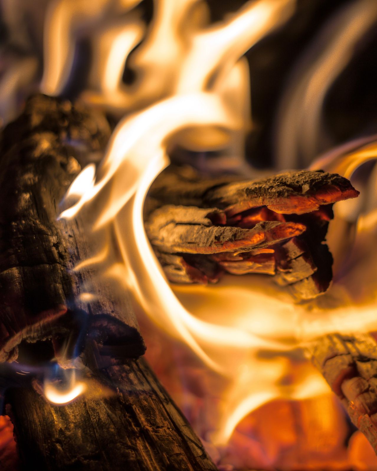 Close-up of wood burning in a fireplace with bright flames and glowing embers.