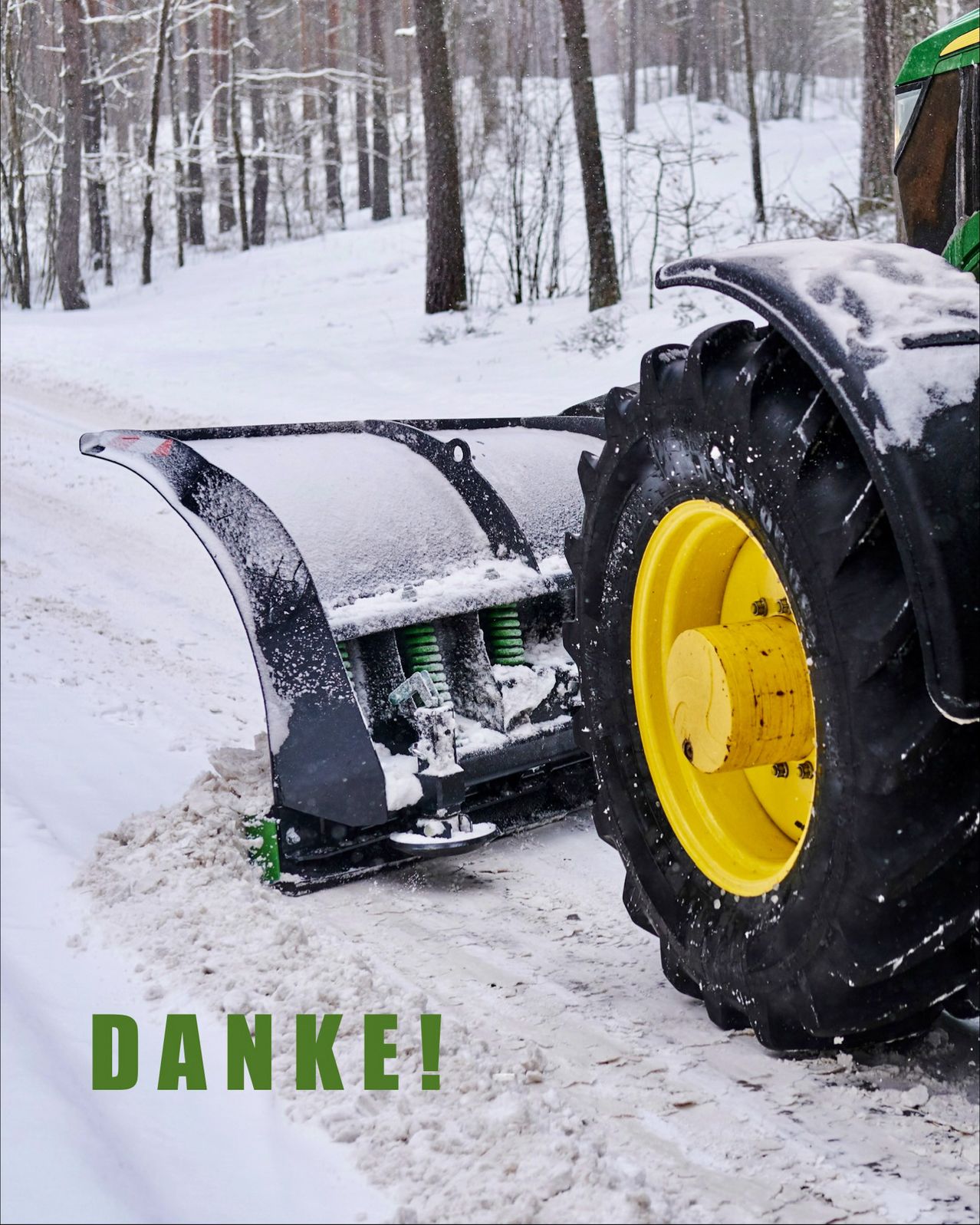 Ein Traktor mit Schneepflug räumt Schnee auf einer verschneiten Straße. Der Schneepflug ist schwarz und hat einen gelben Rand. Das Rad des Traktors ist ebenfalls gelb. Das Wort Danke ist in Grün geschrieben.