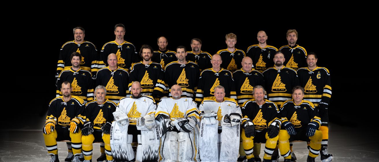 Das Eishockeyteam posiert für ein Foto in ihren Uniformen, wobei die Torhüter vorne stehen und nach vorne blicken.