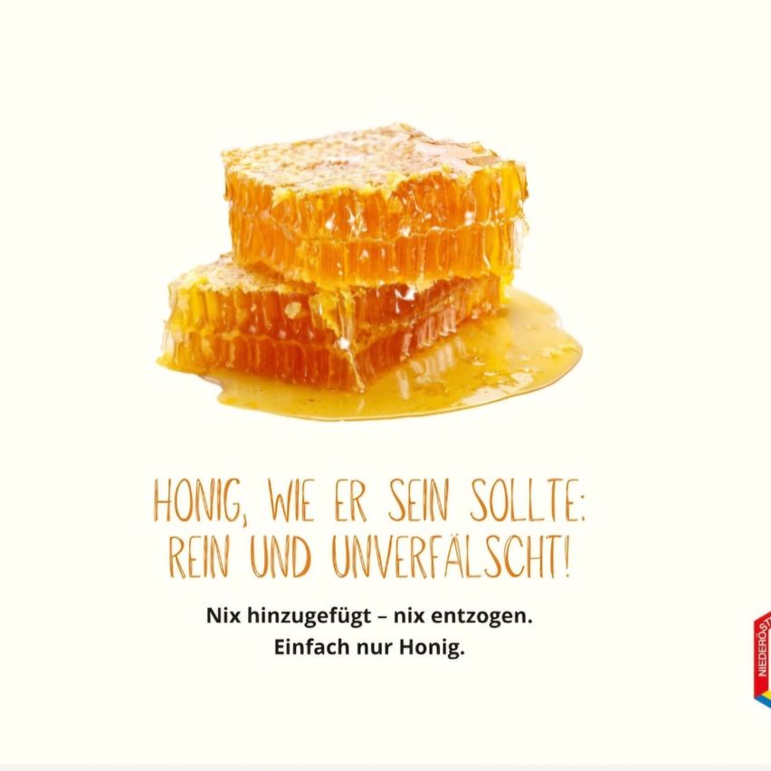Ein Nahaufnahme von gestapelten Honigwaben mit einem deutschen Slogan darunter. Der Honig ist golden und tropft leicht.